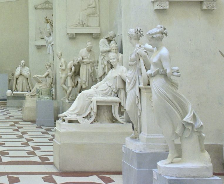 Kunstvolle weiße Skulpturen in einem hellen Museum mit Fliesenboden.